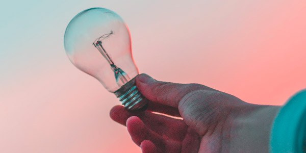 Image of someone holding a lightbulb against the sunset